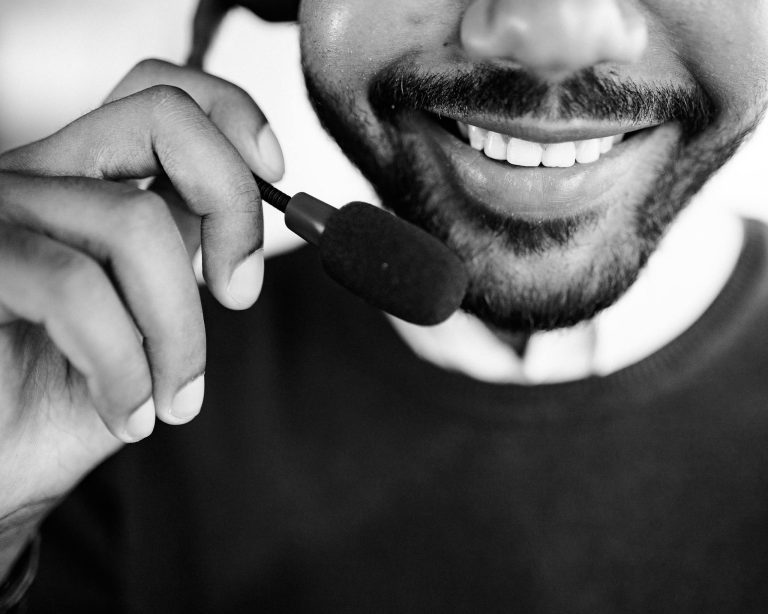 Close-up of a smiling call center agent holding a headset microphone.