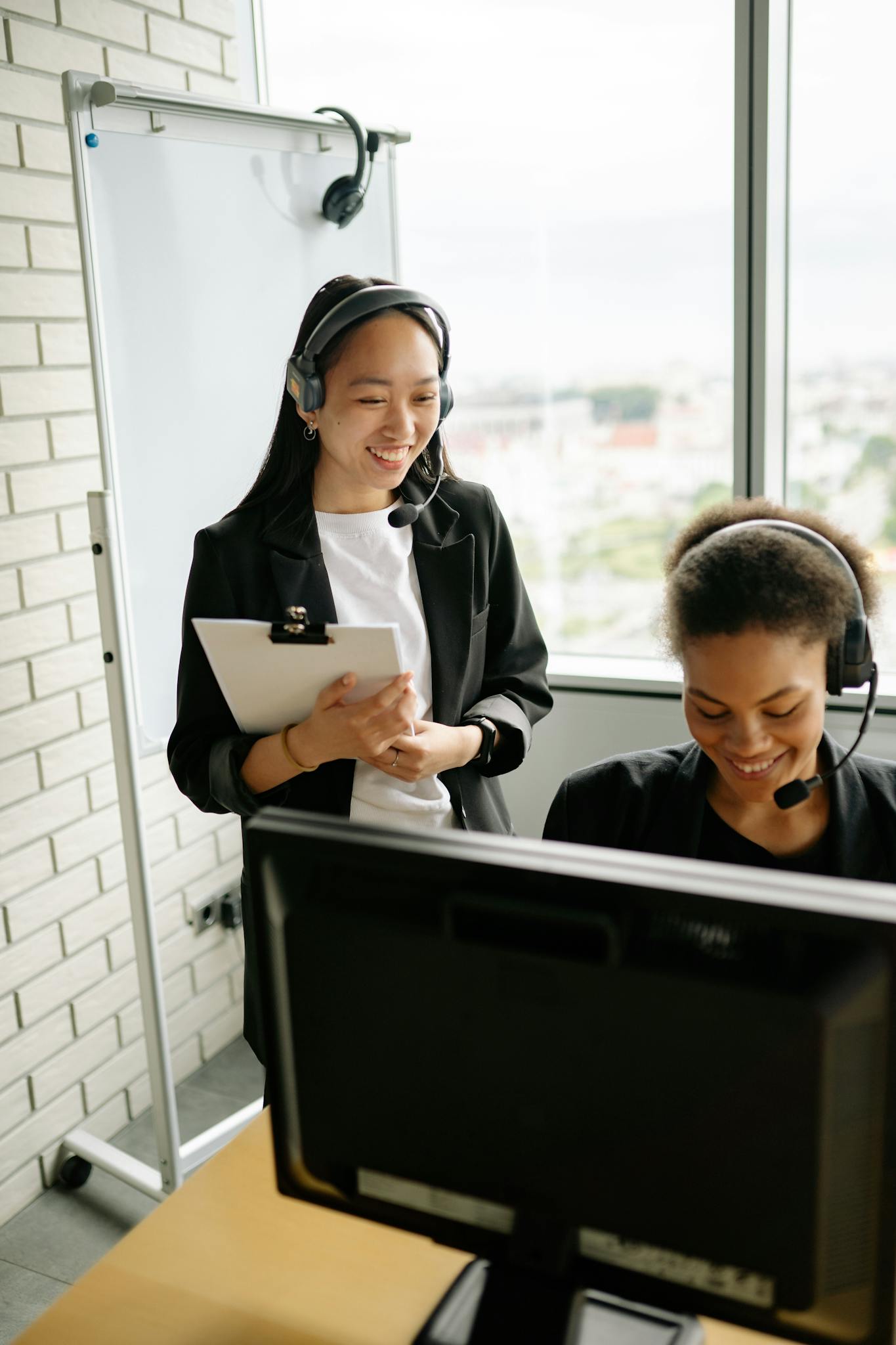 Two call center agents collaborating at their desks with headsets, showcasing teamwork and productivity.