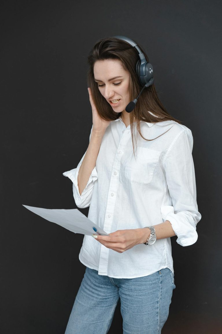 Woman wearing a headset and reading a document, providing customer service support.